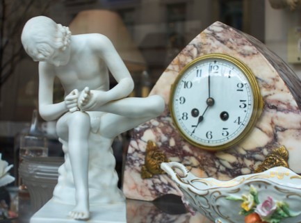 Eine alte Tischuhr mit der antiken Abbildung eines jungen sitzenden Mannes