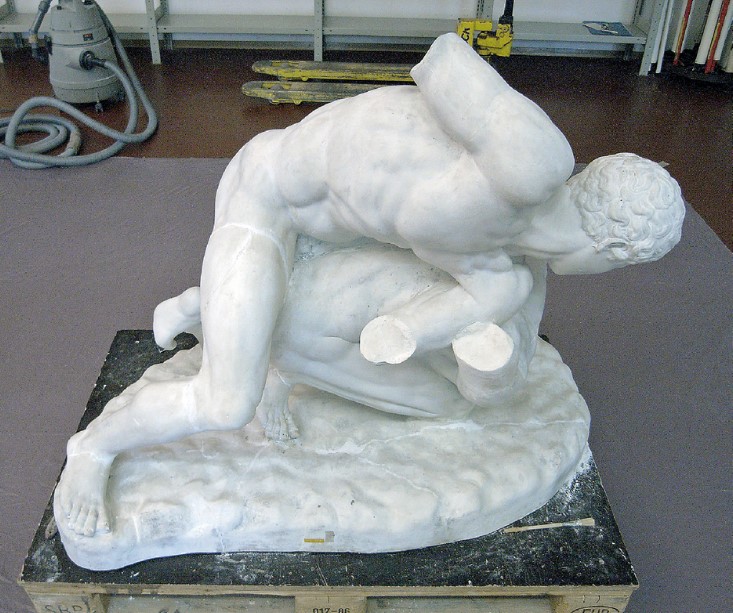 Zwei junge Männer ringen auf dem Boden, es fehlen die Arme